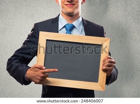 Young businessman holding blank chalkboard. Place for text