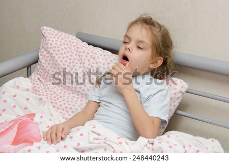 Six year old girl coughs diseased lying in bed with a thermometer on the mouse Royalty-Free Stock Photo #248440243