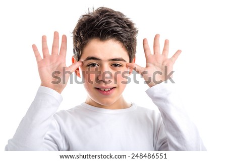Funny Caucasian smooth-skinned teen in a white long sleeved t-shirt smiles grimacing and waving hands next to face
