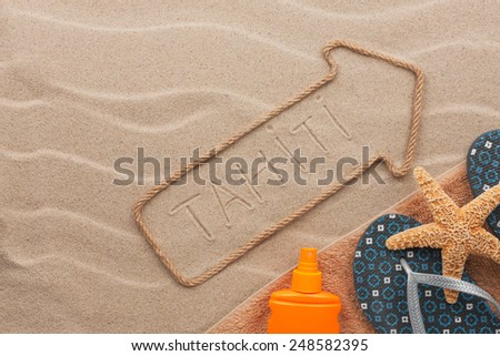 Tahiti pointer and beach accessories lying on the sand, as background