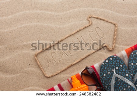 Acapulco pointer and beach accessories lying on the sand, as background