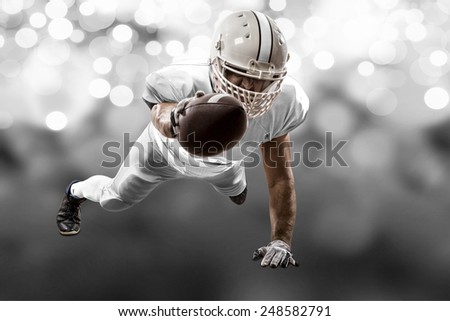 Football Player with a white uniform scoring on a white lights background.