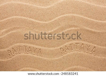 Pattaya inscription on the wavy sand, as background 