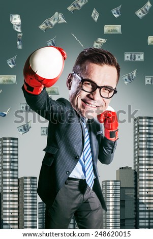 excited happy businessman  with boxing gloves and with big head standing under dollar's rain and looking up. funny picture over dark background
