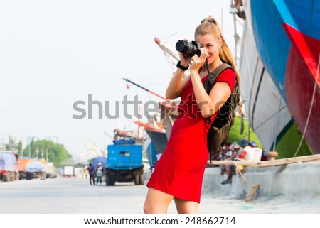 Woman photographing ships while sightseeing at harbour in Jakarta Sunda Kelapa 