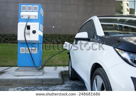 Power supply for electric car charging. Electric car charging station. Close up of the power supply plugged into an electric car being charged. Royalty-Free Stock Photo #248681686
