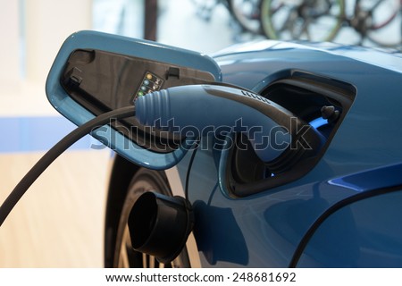 Power supply for electric car charging. Electric car charging station. Close up of the power supply plugged into an electric car being charged. Royalty-Free Stock Photo #248681692