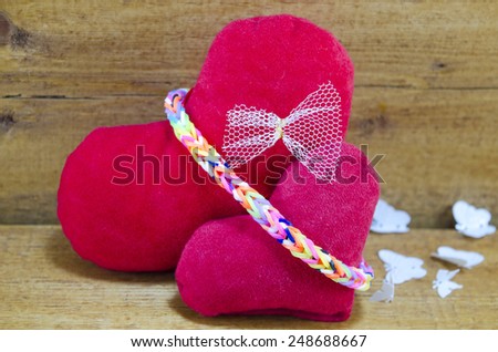Two stuffed hearts on a wooden surface with paper butterflies in the background