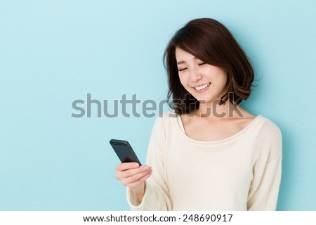 attractive asian woman using smart phone isolated on blue background Royalty-Free Stock Photo #248690917