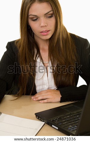 Attractive young brunette woman in business suit sitting at a desk and looking at a computer screen