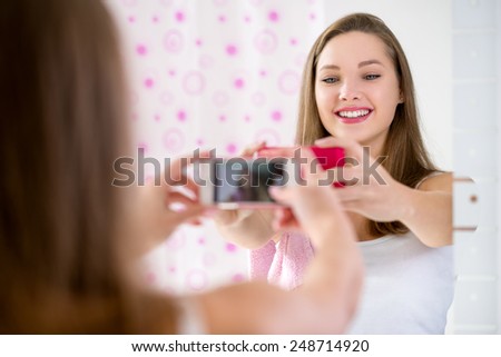 young  teenager girl taking selfie in bathroom  with smartphone 