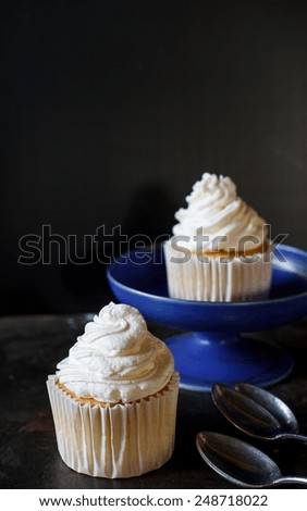 vanilla sweet cupcake with italian butter cream serve on blue plate , image dark tone