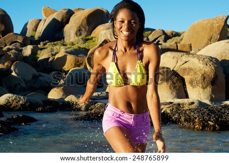 Portrait of a african american woman smiling and splashing water at the beach