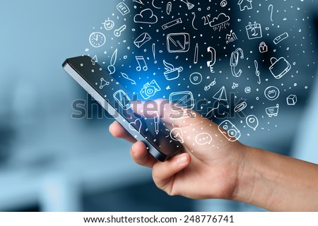 Hand holding smartphone with hand drawn media icons and symbols concept Royalty-Free Stock Photo #248776741
