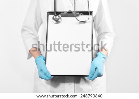 Doctor holding clipboard on light background