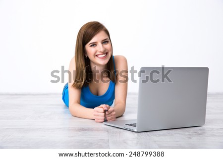Portrait of a cheerful woman lying on the floor with laptop
