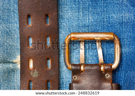 Aged leather belt with a buckle on the jeans background