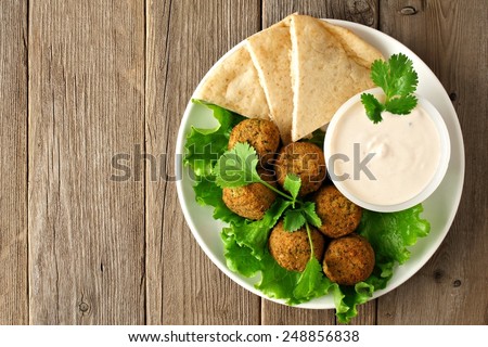 Plate of falafel with pita bread and tzatziki sauce on wooden table. View from above Royalty-Free Stock Photo #248856838