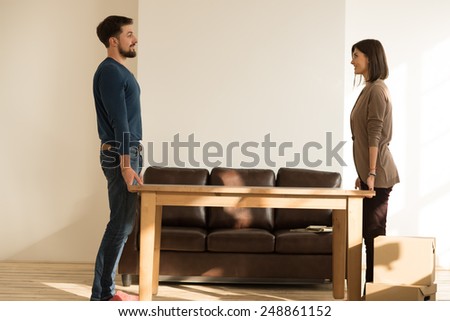 Young couple moving in new house and placing table  Royalty-Free Stock Photo #248861152