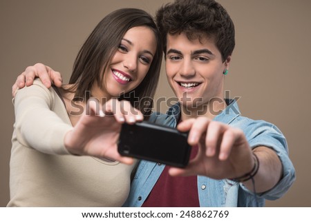 Young cheerful couple taking self pictures with a smart phone