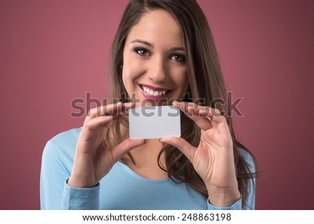 Smiling young woman holding a blank business card and looking at camera