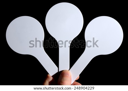 Hand holds three round white card on a black background