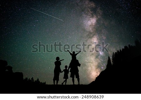 Happy family silhouette with Milky Way and beautiful night sky full of stars in background