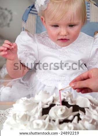 girl looks at candle on cake for birth day
