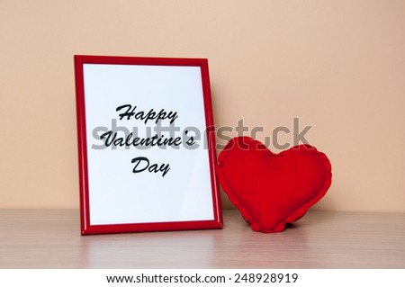 Red photo frame and heart on wooden table. Valentines day concept.