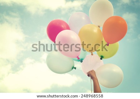 Girl hand holding multicolored balloons done with a retro vintage instagram filter effect, concept of happy birth day in summer and wedding honeymoon party (Vintage color tone) Royalty-Free Stock Photo #248968558