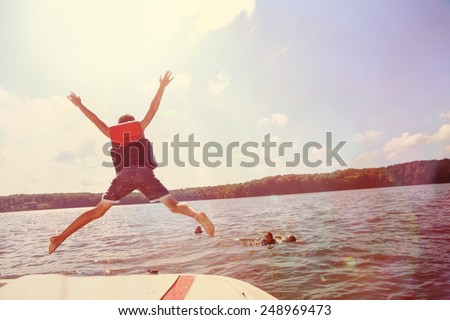 Kids jumping off a boat into the lake. Instagram effect. Royalty-Free Stock Photo #248969473