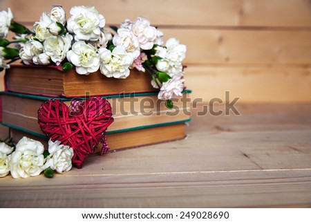 gentle carnation in the old book on a wooden background. Valentine's Day