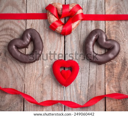 Honey cakes heart shape on wooden background with red ribbons.