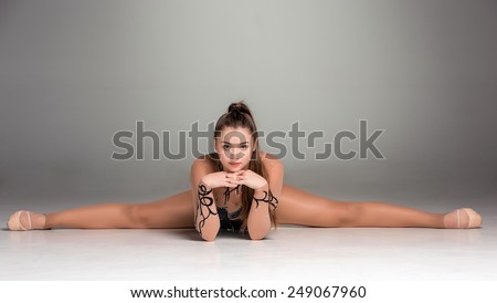 portrait of a gymnast stretching twine on a gray background