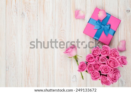 Valentines day background with gift box full of pink roses over wooden table. Top view with copy space
