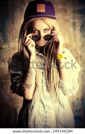 Modern teenage girl with blonde dreadlocks over grunge background. Jeans style. Modern generation.
