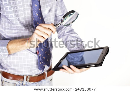 Businessman hand holding magnifier over tablet pc
