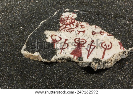 stone with ancient images on the black sand