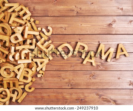 Word drama made with block wooden letters next to a pile of other letters over the wooden board surface composition