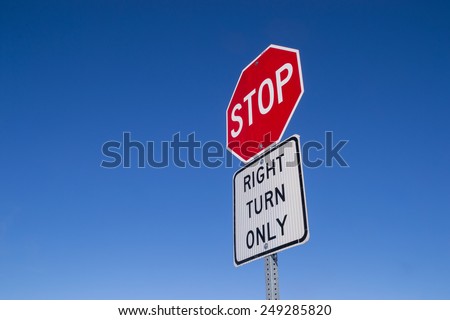 The "Stop, right turn only" street sign with blue sky background.