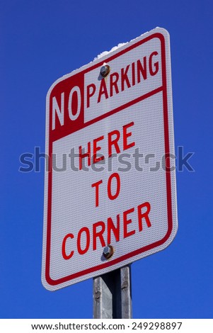 The "No Parking here to corner" sign with blue sky background.