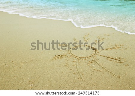 a sun drawn in the sand on the seashore
