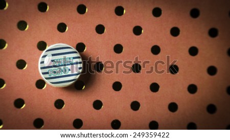 Round cute thumbtack or pushpin for whiteboard, notice board, gift card or special occasions with Wish For You message on polka dot vintage patterns background. Slightly defocused and close-up shot