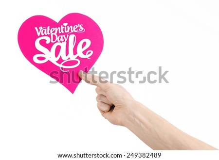 Valentine's Day and sale topic: Hand holding a card in the form of a pink heart with the word Sale isolated on white background in studio