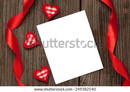 Empty white isolated frame with hearts and ribbons for valentine's day on dark wooden background
