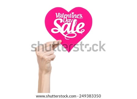 Valentine's Day and sale topic: Hand holding a card in the form of a pink heart with the word Sale isolated on white background in studio