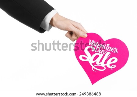 Valentine's Day and sale topic: Hand of a man in a black suit holding a card in the form of a pink heart with the word Sale isolated on white background in studio.
