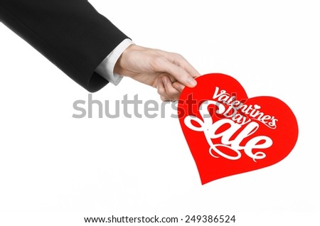Valentine's Day and sale topic: Hand of a man in a black suit holding a card in the form of a red heart with the word Sale isolated on white background in studio.