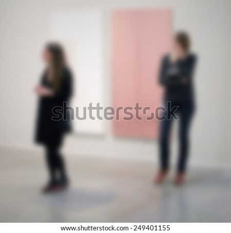 Not recognizable women visit an art gallery. Intentionally blurred post production background.