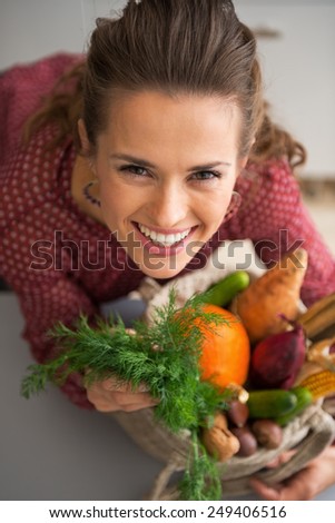 Portrait of happy young housewife with shopping bag of fresh vegetables from local market